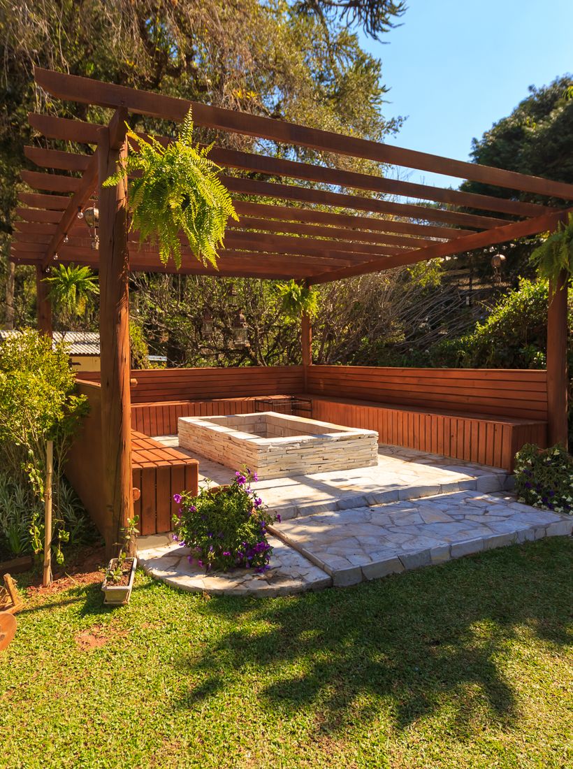 A wooden gazebo set in a lush green garden
